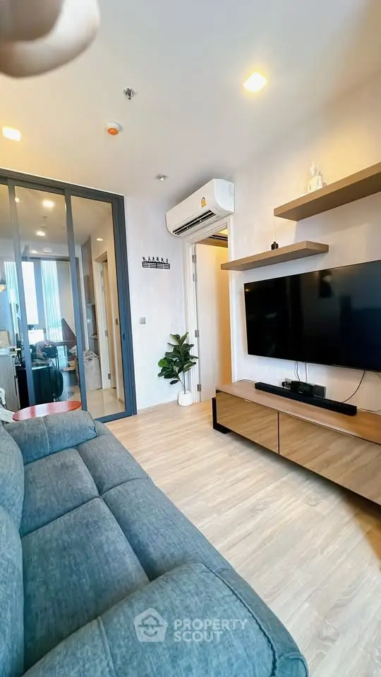 Modern living room with sleek design, featuring a wall-mounted TV, stylish shelving, and cozy seating.