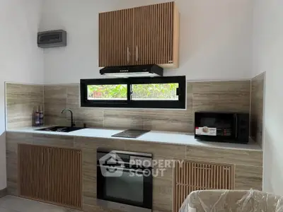 Modern kitchen with sleek cabinetry, built-in oven, and microwave, featuring a minimalist design and natural light.
