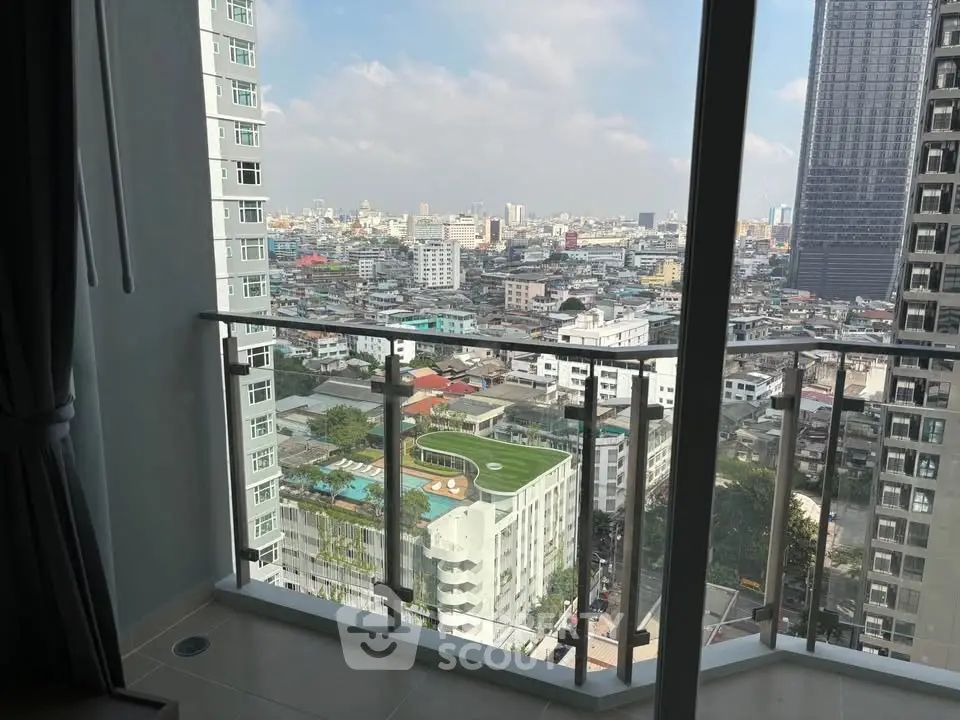 Stunning cityscape view from a high-rise balcony with glass railing, showcasing urban living at its finest.