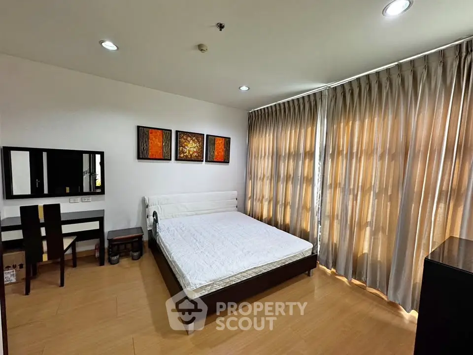 Spacious bedroom with modern decor and large windows for natural light.