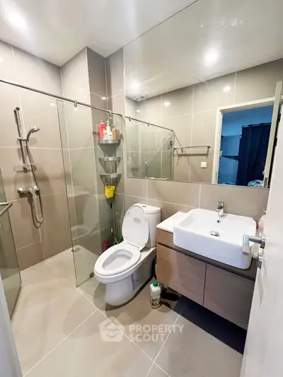 Modern bathroom with glass shower and sleek fixtures in contemporary home.