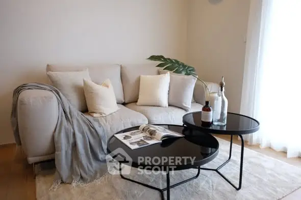 Stylish living room with cozy beige sofa and modern black coffee tables.