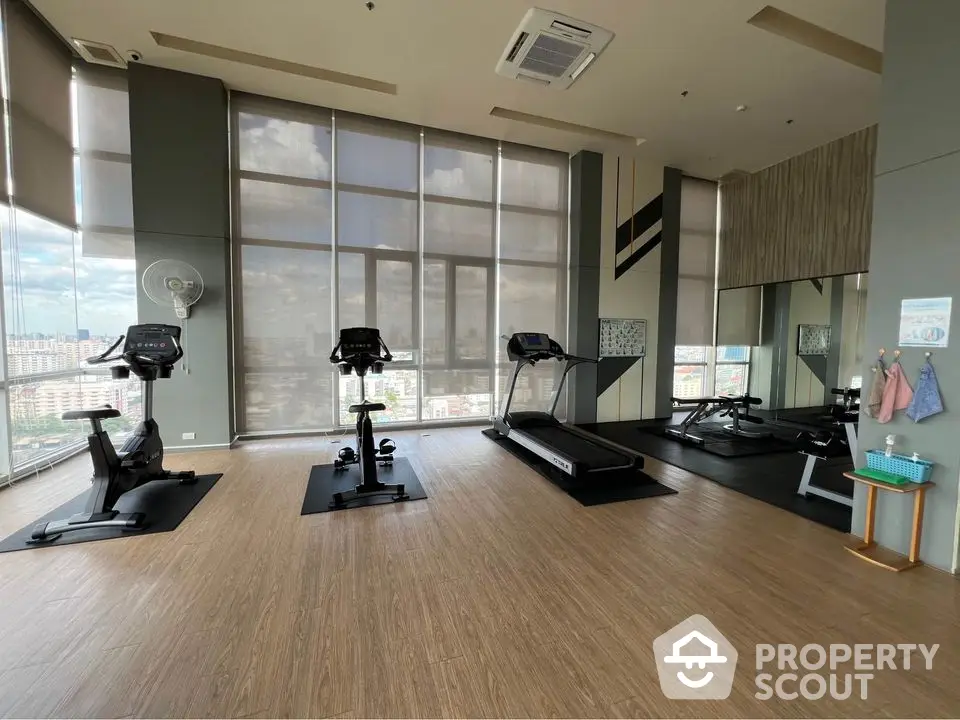 Spacious gym with modern equipment and city view in luxury apartment complex