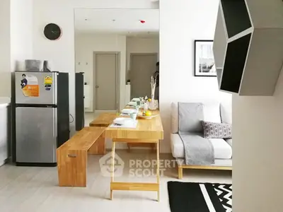 Modern open-plan living room with dining area and compact kitchen featuring sleek furniture and decor.