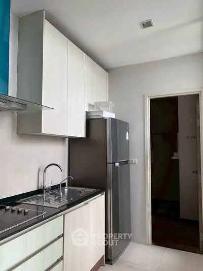 Modern kitchen with sleek cabinets and stainless steel fridge in a stylish apartment.