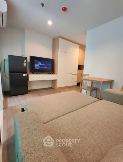 Modern living room with cozy sofa, flat-screen TV, and sleek storage cabinets in a stylish apartment.