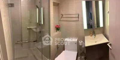 Modern bathroom with glass shower and sleek vanity in contemporary apartment.