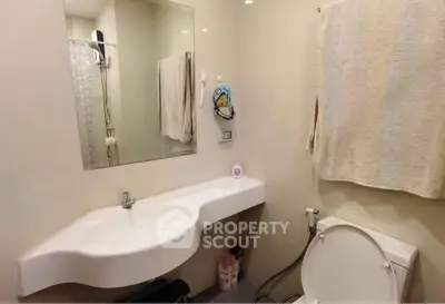 Modern bathroom with sleek white sink and wall-mounted mirror, featuring neutral tones and contemporary design.
