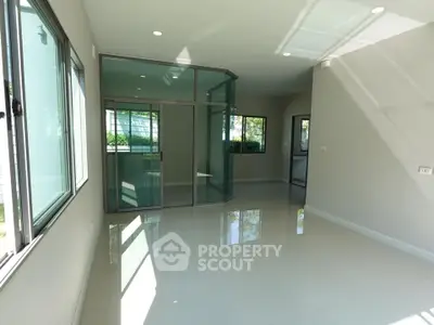 Spacious modern living room with large windows and glass doors, offering abundant natural light.