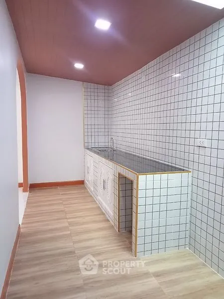 Modern minimalist kitchen with tiled walls and wooden flooring