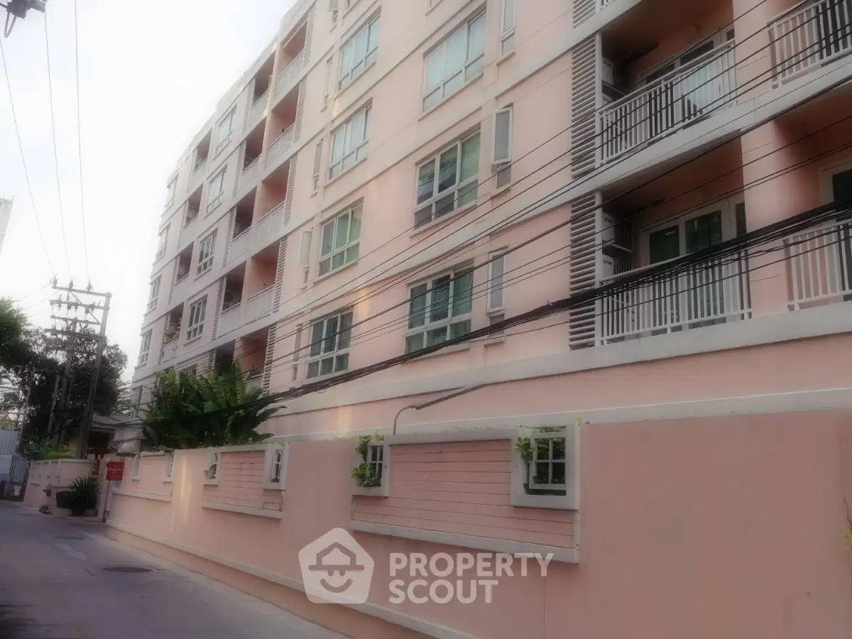 Modern apartment building exterior with balconies and lush greenery, ideal urban living space.