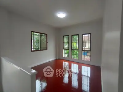 Spacious living room with polished wooden floors and large windows offering natural light.