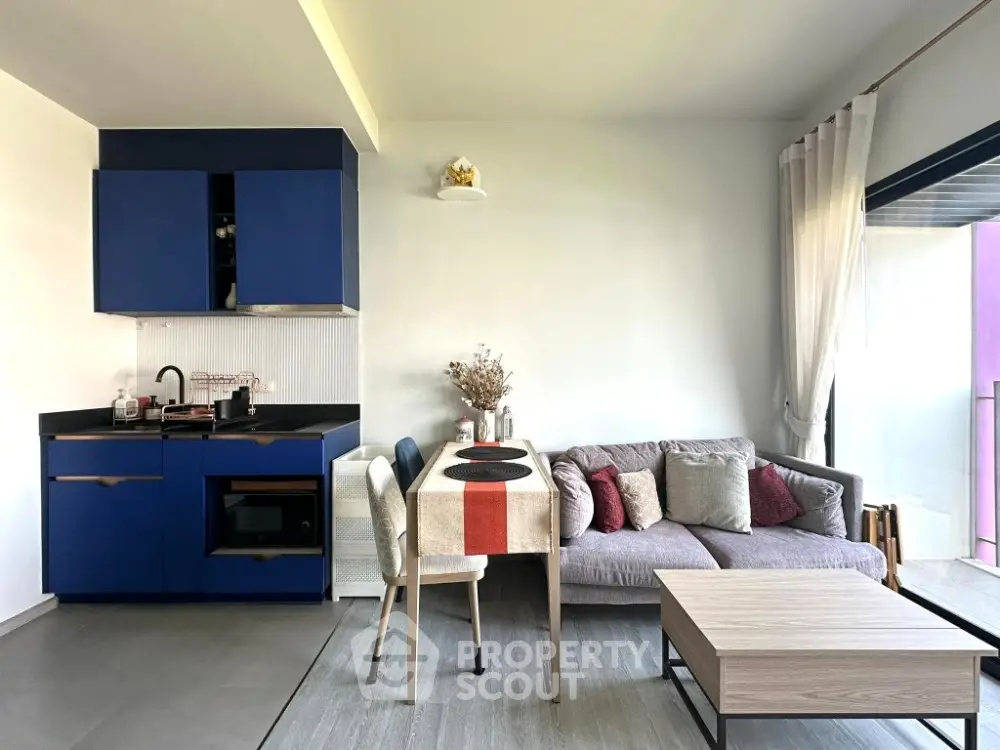 Modern open-layout living room with stylish blue kitchen cabinets and cozy dining area.