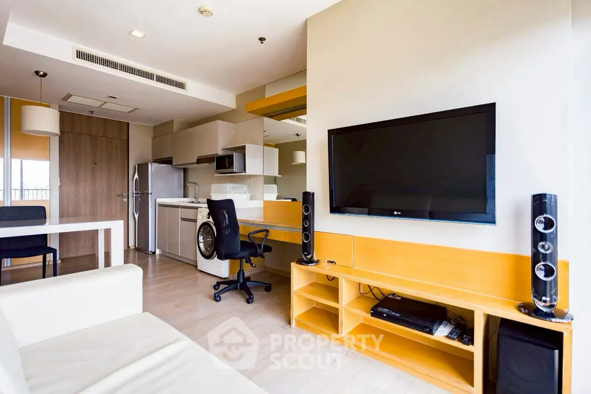 Modern living room with sleek entertainment setup and open kitchen layout.