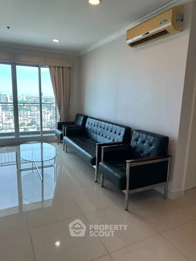 Modern living room with sleek black leather sofas and city view from large windows.