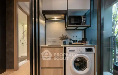 Modern compact kitchen with washing machine and microwave in stylish apartment