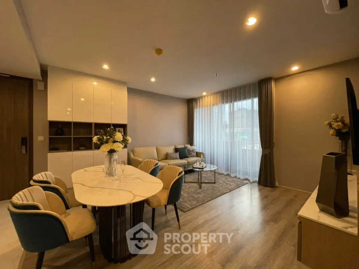 Modern living room with elegant dining area and large window, featuring stylish decor and cozy ambiance.