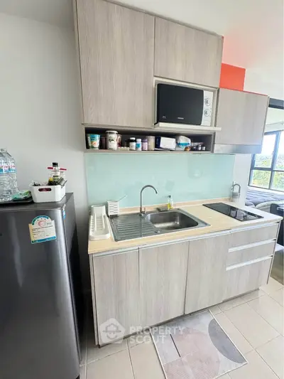 Modern compact kitchen with sleek cabinetry and appliances in a bright apartment setting.