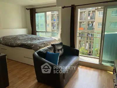 Cozy studio apartment with large windows and modern furnishings, offering a bright and inviting living space.