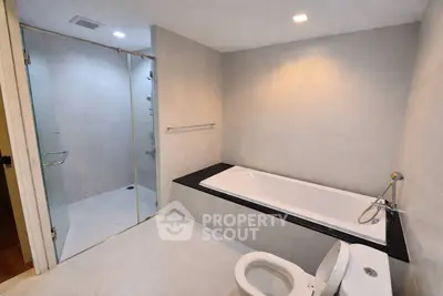 Spacious modern bathroom with glass shower and sleek bathtub