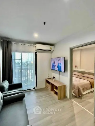 Modern living room with sleek furniture and a view into a cozy bedroom