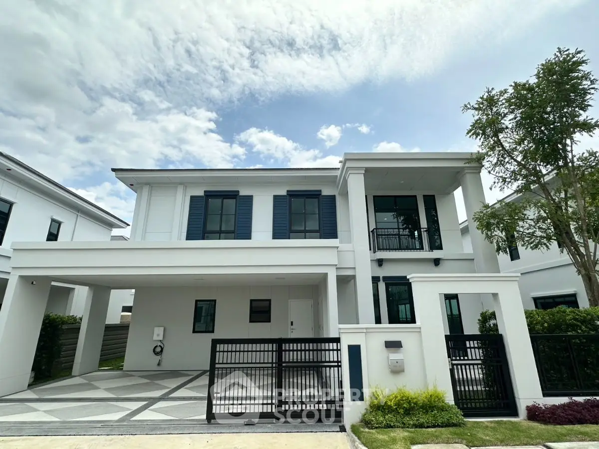 Modern two-story house with sleek design and spacious driveway under a clear sky.
