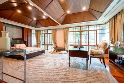 Luxurious bedroom with wooden ceiling and large windows offering a serene garden view.