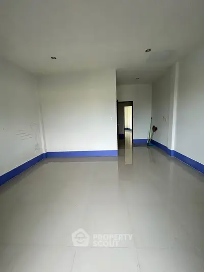 Spacious empty room with tiled flooring and blue trim, ready for customization.