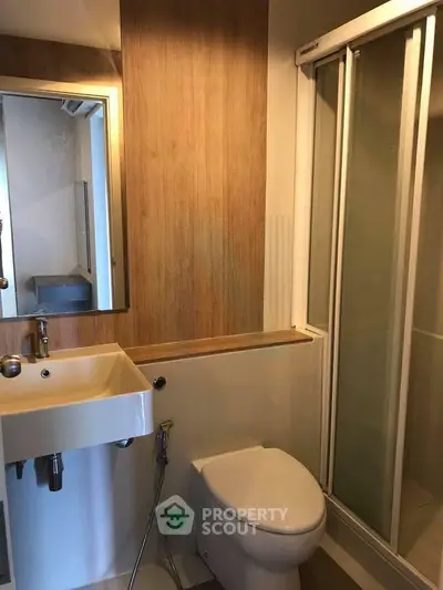 Modern bathroom with sleek design featuring a shower, sink, and toilet in a compact space.