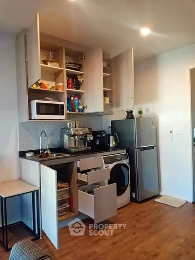 Modern kitchen with open cabinets, washing machine, and stainless steel appliances.