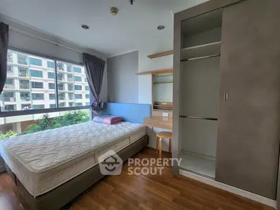 Modern bedroom with large window and built-in wardrobe in urban apartment
