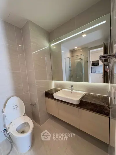 Modern bathroom with sleek fixtures and large mirror in a contemporary apartment.