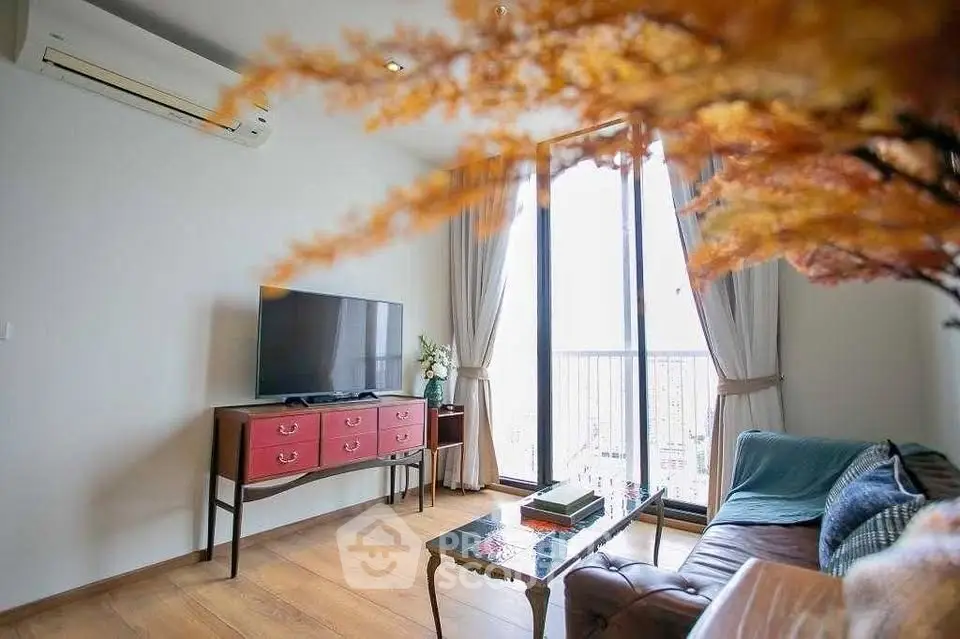 Charming living room with large window and stylish decor, featuring a cozy sofa and modern TV setup.