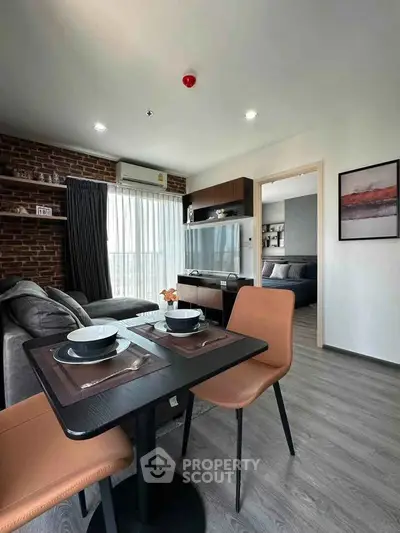 Modern living room with dining area in stylish apartment featuring brick accent wall and sleek furniture.