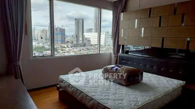 Modern bedroom with city view and stylish decor, featuring a large window and contemporary furnishings.