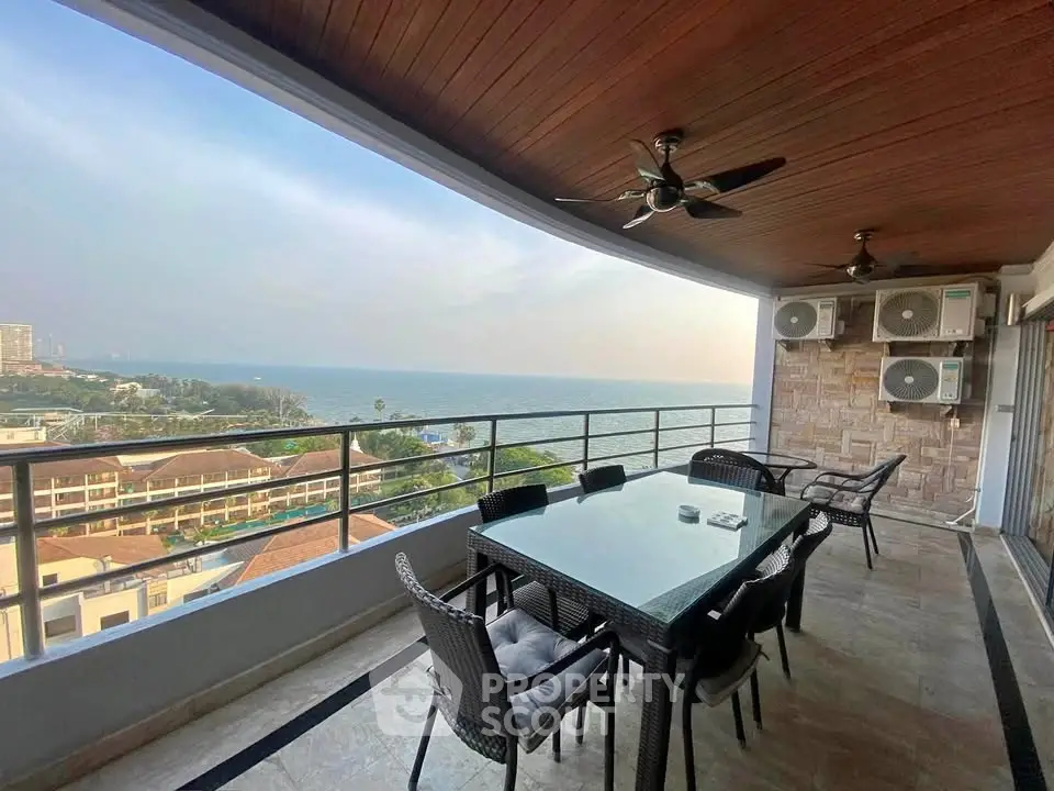 Stunning ocean view from spacious balcony with modern dining set and ceiling fans.