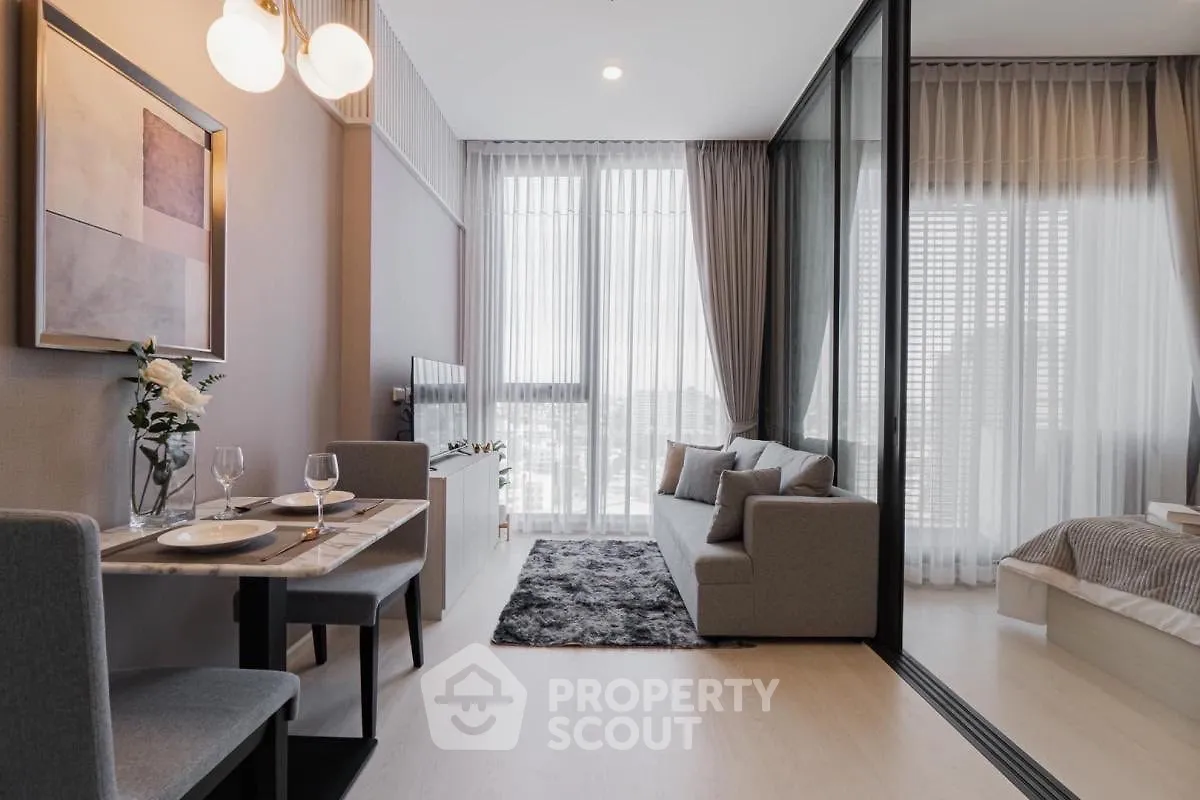 Modern open-plan living room with dining area and large windows in a stylish apartment.