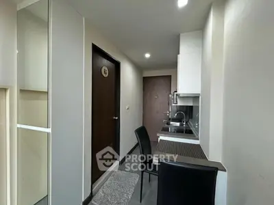 Compact modern kitchen with sleek design and dining area in cozy apartment.