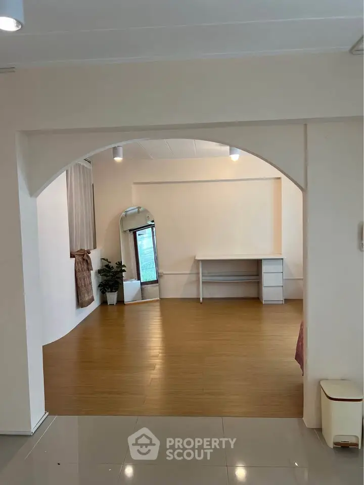 Spacious interior with wooden flooring and archway, ideal for versatile living space.