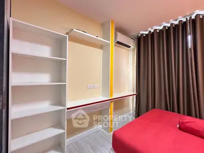 Modern bedroom with built-in shelves and air conditioning, featuring a vibrant red bedspread and floor-to-ceiling curtains.
