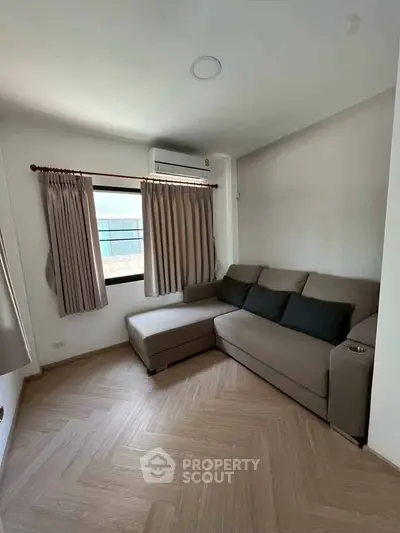 Cozy living room with modern sofa and natural light, perfect for relaxation.