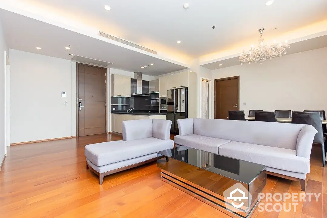 Spacious modern living room with gleaming hardwood floors, elegant furniture, and an open-plan kitchen, perfect for entertaining.