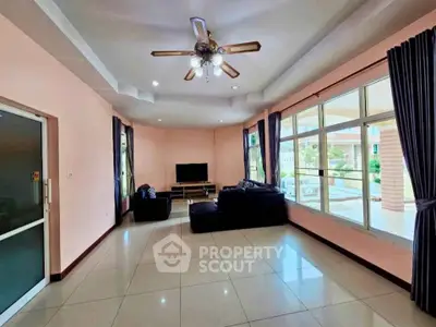 Spacious living room with large windows and modern ceiling fan, perfect for family gatherings.
