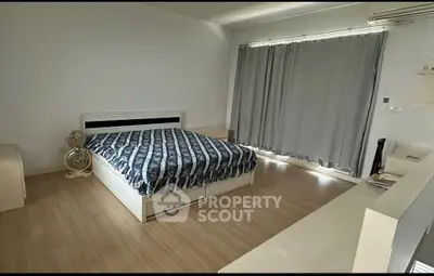 Spacious bedroom with modern decor and large window, perfect for comfort and relaxation.