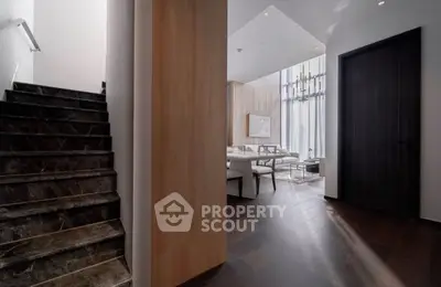 Luxurious modern interior with elegant staircase and spacious living area, featuring high ceilings and stylish decor.