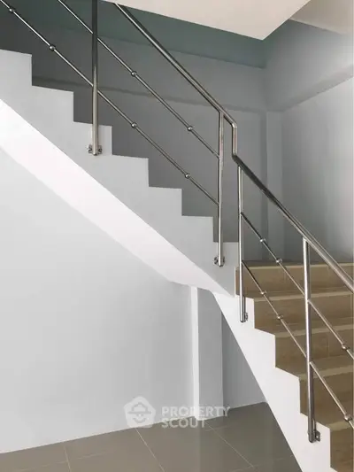 Modern staircase with sleek metal railing in a contemporary building interior.