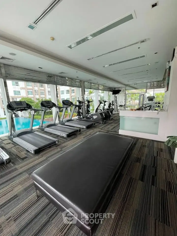 Modern gym with treadmills and pool view in luxury apartment complex