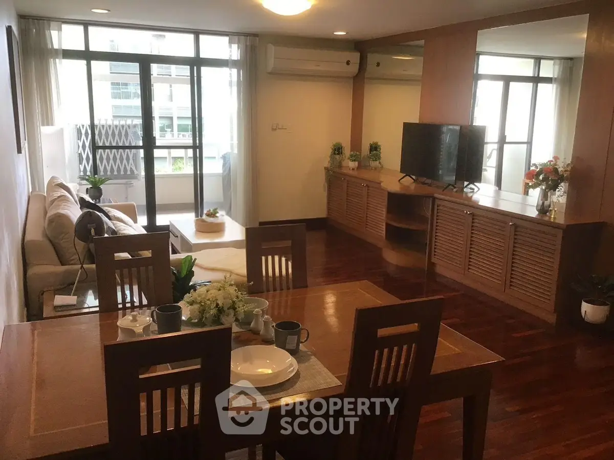 Spacious living room with elegant wooden flooring and modern decor, featuring a cozy dining area and large windows.