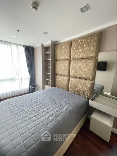 Spacious bedroom with modern decor and large window offering natural light.