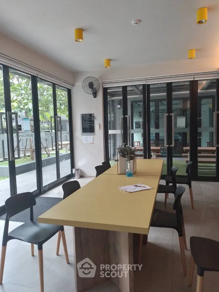 Modern communal area with large table and glass doors in a stylish building.